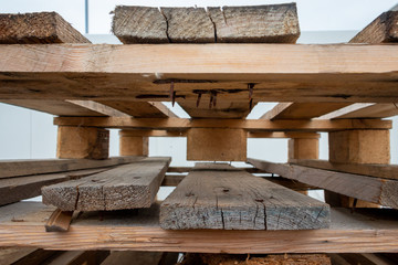 stacked pallets with wooden planks and rusty nails and screws, stored for reuse
