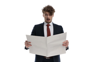 Surprised businessman reading newspaper and gasping