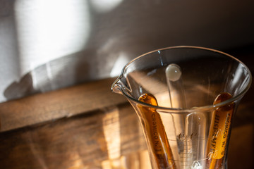 Glass ampoules containing silk sutures from the 1950s in a graduated cup. It is a way of containing...