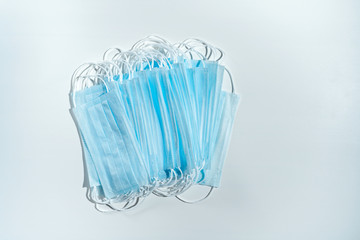 Stack of disposable medical masks on a blue background. Face mask for protection virus, flu,...