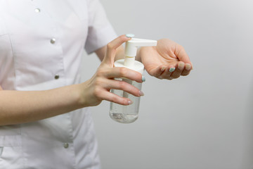 The girl is holding a liquid in a bottle. A doctor in a medical gown applies a disinfectant to his hands against bacteria and viruses. A nurse in white applies an antibacterial agent to her hands.