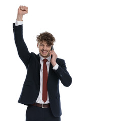 Businessman talking on phone, celebrating with fist in the air