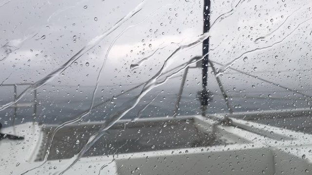 View through window of boat, storm in the Adriatic Sea nearby coast of Croatia, strong heavy rain through catamaran windows, the stormy sky, drops on the window