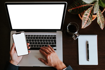 businessman using phone and laptop in office with pen notebook and coffee cup background. layout of multiple device phone with pen planning notebook. office mockup with several devices.