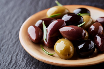 Various olives on black stone background. Close up. 