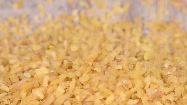 Close up yellow bulgur falling on wooden table