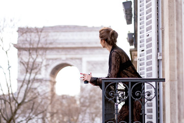 Attractive  yang woman in pajama is drinking coffee on balcony in the morning in city Paris. view...
