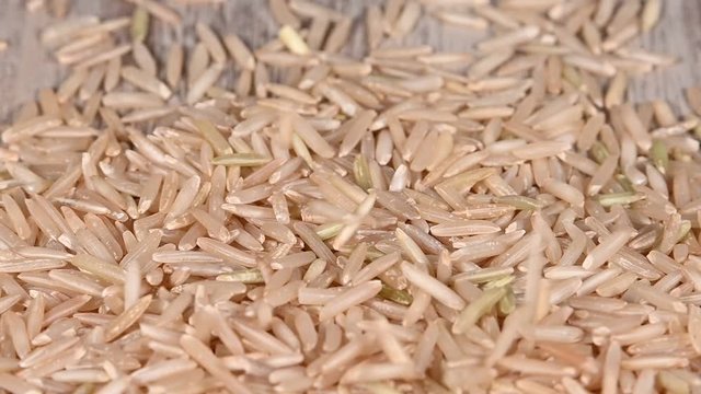Close up brown rice falling on wooden table
