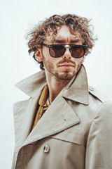 Portrait of a handsome casual guy with curly hair posing in the bright studio while looking serious