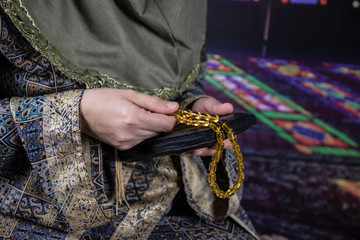 Muslim woman praying for Allah muslim god at room near window. Hands of muslim woman on the carpet praying in traditional wearing clothes, Woman in Hijab, Carpet of Kaaba, Selective focus, toned