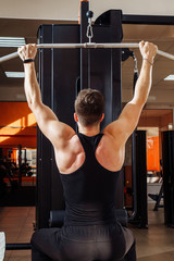Shoulder pull down machine. Fitness man working out lat pulldown training at gym. Upper body...