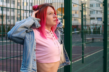 Stylish woman with pink hair outdoors