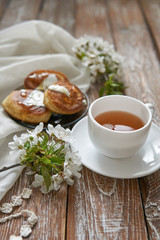 Pile of small homemade pancakes with honey, tea cup and honeycomb on wooden table