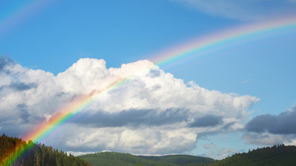 Detail of a rainbow in front of a cumulonimbus cloud and blue sky