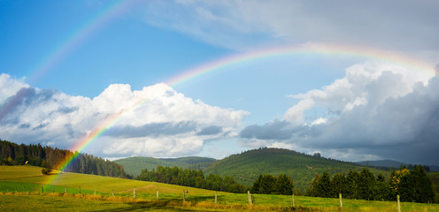 Rainbow over rural landscape in a low mountain range in autumn, Germany