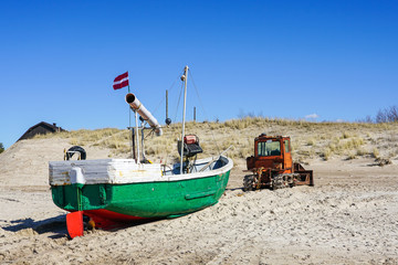 Fototapeta na wymiar a heavy bulldozer pulls a fishing boat out of the sea