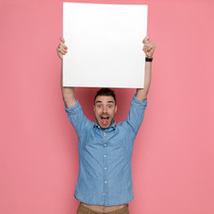 excited casual man holding a blank board overhead