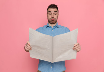 casual man reading newspaper and blowing cheeks