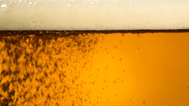 Close up pouring beer with bubbles in glass