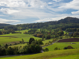 Fototapeta na wymiar Weitläufige Landschaft in der Rhön - Wiesen und Wald mit blauen Himmel und Wolken