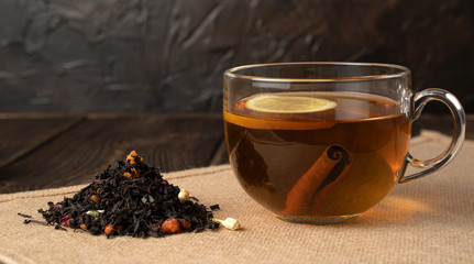 A Cup with fragrant flower tea, lemon, cinnamon and a scattering of leaf tea on a natural background. The concept of relaxation, eating.