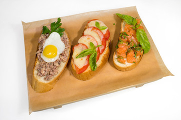 Three different sandwiches on the shelf. Slice of loaf with canned fish in oil and egg. Slice of loaf with tomato and melted cheese. Slice of loaf with salmon and herbs.