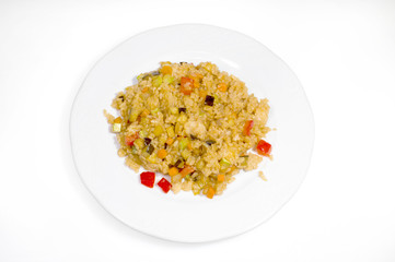 Boiled rice with slices of vegetables on a white plate on a white background