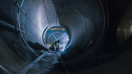 Professional Heavy Industry Worker Wearing Helmet Welding Inside Oil and Gas Pipe. Construction of the Oil, Natural Gas and fuels Transport Pipeline. Industrial Manufacturing Factory