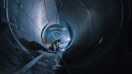Professional Heavy Industry Worker Wearing Helmet Welding Inside Oil and Gas Pipe. Construction of...