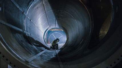 Professional Heavy Industry Welder Working Inside Pipe, Wears Helmet and Starts Welding. Construction of the Oil, Natural Gas and Fuels Transport Pipeline. Industrial Manufacturing Factory.