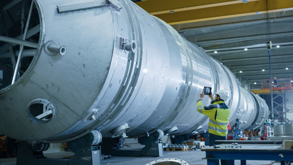 Heavy Industry Engineer Uses Augmented Reality Digital Tablet to Scan Large Diameter Pipe. Modern Industrial Manufacturing Technology to Design and Construct Oil, Gas and Fuels Transport Pipeline.