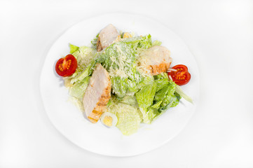 Lettuce and young cabbage salad with slices of grilled pork garnished with grated cheese, quail eggs and tomatoes on a white plate not white background