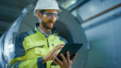 Portrait of Professional Heavy Industry Engineer / Worker Wearing Safety Uniform and Hard Hat Uses...