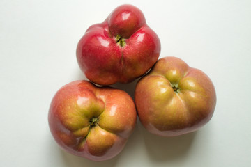 Three curves of ripe red apples close-up isolated and copy space. Trend-ugliness