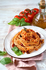 Pasta with tomato sauce, sun-dried tomatoes and olives on a light background
