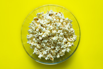 Popcorn close up in a clear glass Cup top view on a bright yellow background