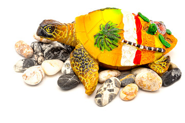 Souvenir turtle with stones around on a white background. Side view. On the yellow shell there are...