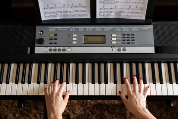 Close up woman's hand playing piano while learning from home during quarantine. Piano student.Top...