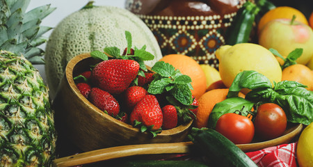 
fruits and vegetables with a bowl with strawberries in the foreground