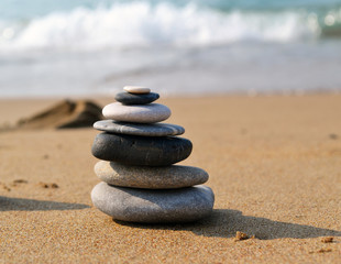Single zen grey stone tower on the sand