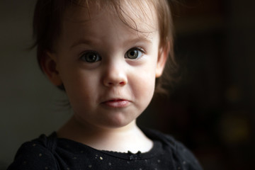 Close-up portrait of a little cute white baby with a dirty face in soft light and blurry background
