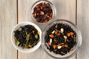 A variety of dry tea in cups with pieces of dried fruit, berries and flowers. The concept for the...