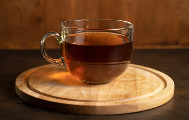 Transparent Cup with fragrant black tea on a blackboard on a natural background. Concept for your design, advertising.