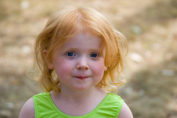 Kleines hübsches rothaariges Mädchen im grünen Badeanzug