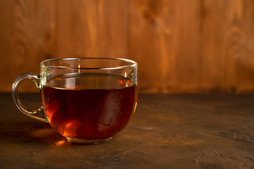 Transparent Cup with fragrant black tea on a blackboard on a natural background. Concept for your design, advertising.