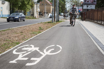 Bicycle sign painted on asphalt in the background a cyclist riding with a mask on his face, due to pandemic Covid-19.