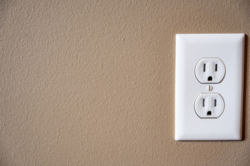white dual electrical outlet with plate cover on beige colored drywall