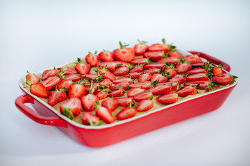 Strawberry pie in red ceramic baking dish on the white background