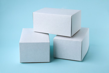 White cardboard boxes with space for text stand on top of each other on a blue background. Boxes for packaging and delivery of goods to order. Selective focus
