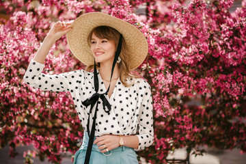 Young beautiful happy smiling girl wearing trendy wide brim straw wicker hat, white polka dot...